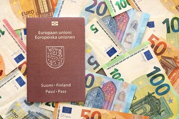 Finland passport lies on big amount of euro money banknotes close up. Rich life and travel in Europe concept