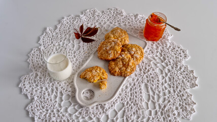 Homemade pumpkin oatmeal cookies with milk, served on a white crochet napkin, top view