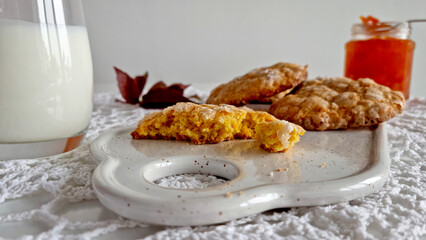 Close up of homemade pumpkin cookies with glass of milk on vintage crochet doily.