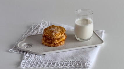Close up of sugar cookies on rectangular plate with glass of milk on vintage linen napkin with lace in minimalist design.