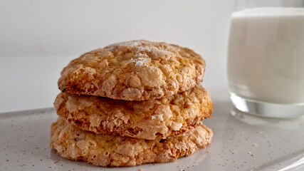 Close-up at eye level of sugar-crusted cookies on white background with glass of milk