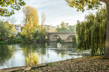 Steinerne Bogenbrücke  aus Quadermauerwerk aus Sandstein und Laubbäumen mit Herbstlaub mit Reflexion in Lauffen am Neckar 