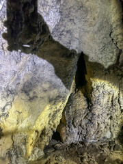 Close-up of a stunning limestone formation inside a natural cave, showing textured mineral layers illuminated by soft light.