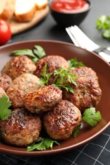 Delicious patties with parsley in bowl on grey table, closeup