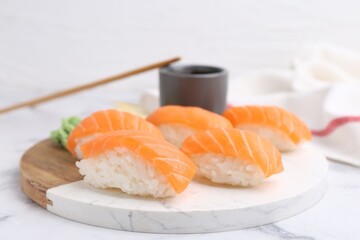 Delicious nigiri sushi with salmon and soy sauce on white marble table, closeup