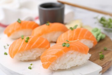 Delicious nigiri sushi with salmon and microgreens on white table, closeup