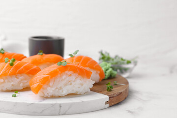 Delicious nigiri sushi with salmon and microgreens on white marble table, closeup. Space for text