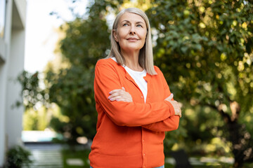 Pretty mature blonde woman in orange shirt looking contented