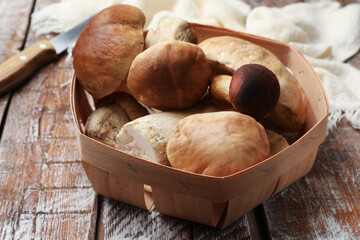 Fresh porcini mushrooms and knife on wooden table, closeup
