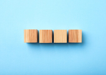 Wooden cubes on light blue background, top view