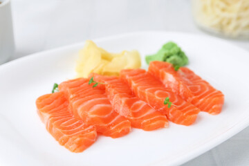 Fresh salmon sashimi with microgreens, wasabi and ginger on light table, closeup