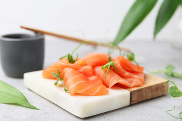 Fresh salmon sashimi with microgreens on grey table, closeup