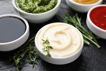 Different sauces and herbs on table, closeup