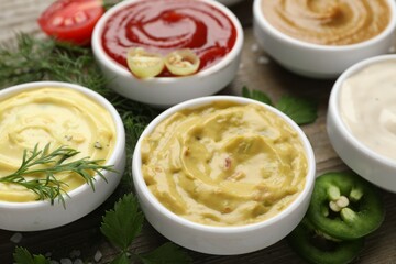 Different sauces and herbs on wooden table, closeup
