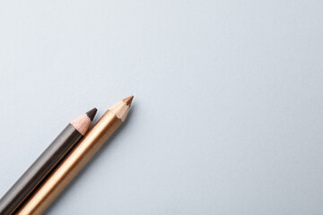 Colorful eye pencils on light background, flat lay. Space for text