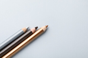 Colorful eye pencils on light background, flat lay. Space for text