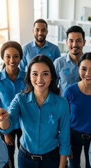 Group of coworkers wearing blue shirts and ribbons in modern office, awareness month concept