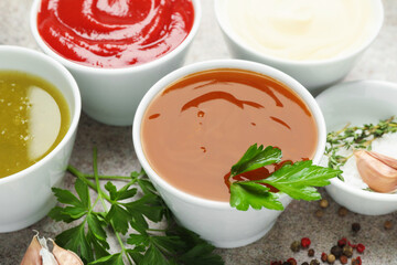 Different sauces, spices and herbs on light table, closeup
