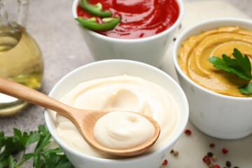 Different sauces, spices and herbs on light table, closeup