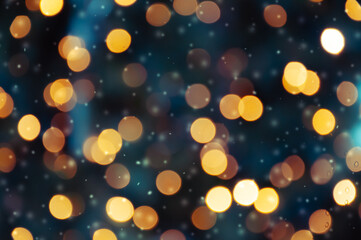 Golden bokeh lights on a dark background. Snowflakes falling down. Christmas magical light background, overlay or lens flare effect