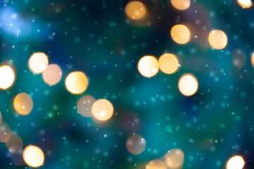 Golden bokeh lights on a dark background. Snowflakes falling down. Christmas magical light background, overlay or lens flare effect
