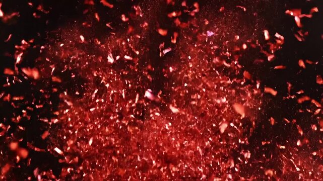 Fiery red particles exploding and swirling against a dark background, creating a vibrant, energetic burst of color.