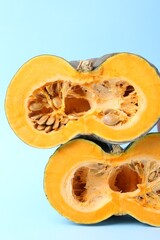 Halves of fresh pumpkin on light blue background, closeup. Gourd family