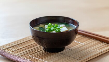 A comforting and healthy bowl of authentic Japanese traditional soup, featuring silken tofu, fresh wakame seaweed, and green onions, served on a bamboo mat