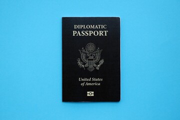 United States diplomatic passport book on light blue paper background close up. Travel document on blue surface