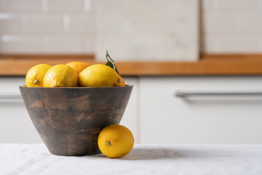Wooden bowl with yellow lemons on linen tablecloth in bright minimalist kitchen interior