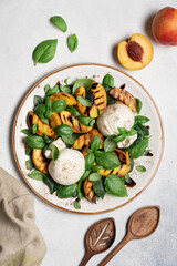 Mediterranean salad with burrata cheese, grilled peaches, fresh basil leaves, olive oil and balsamic glaze, gourmet summer dish on light background