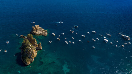 Aerial view of the Faraglioni rocks located in the Bay of Scopello, in the province of Trapani, Sicily, Italy. There are boats on holiday among the cliffs.