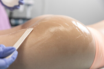 Girl in a beauty salon. Preparing for the procedure. Beautician applies the gel to girl bottom. Concept of body care, hygiene, skin, hardware cosmetology.