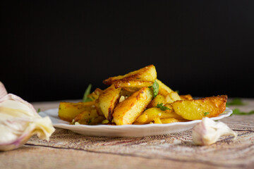 Baked potatoes with garlic, herbs and seasonings on a black background