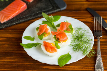 Boiled eggs with pieces of fish and herbs on top