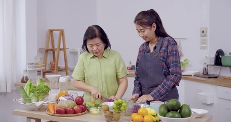Senior asian mother adult daughter making salad side by side, both chopping vegetable and fruit on table, teamwork, healthy lifestyle, family bonding, joyful home cooking moment, - Powered by Adobe