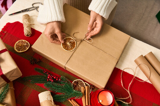 Hands meticulously wrapping a Christmas gift with festive decor and holiday cheer