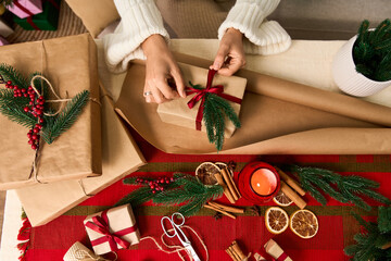 Wrapping festive gifts in cozy holiday atmosphere with decorations and seasonal cheer