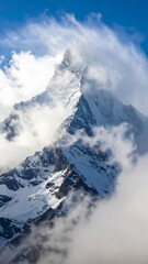 Dramatic view of a majestic snow covered mountain peak piercing through the clouds.