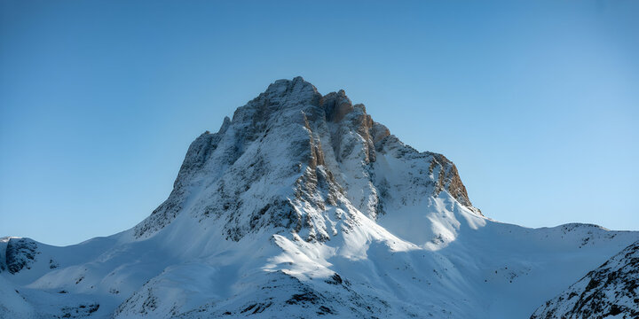 Majestic snow-covered mountain peak piercing a clear blue sky with rugged terrain below - Powered by Adobe