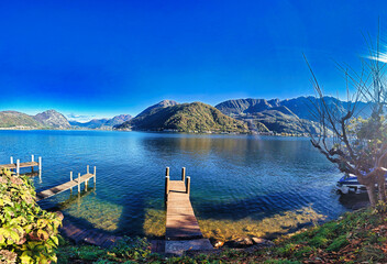 Aerial drone panoramic view of Lake Ceresio (Lake Lugano), alpine landscape between Switzerland and Italy on a sunny day.