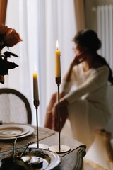 Candles illuminating a pensive woman at dinner table