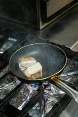 Tuna piece in pan over fire in restaurant kitchen