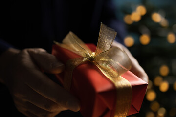 Man holding Christmas gift near tree
