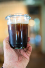Iced Americano in disposable cup on man hand. Close up