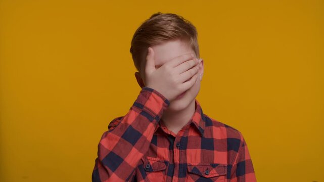 Boy Showing Facepalm Gesture at Camera on Yellow Background