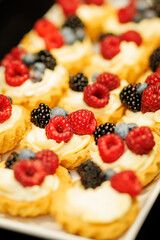 Mini tartlets with cream and fresh berries on tray