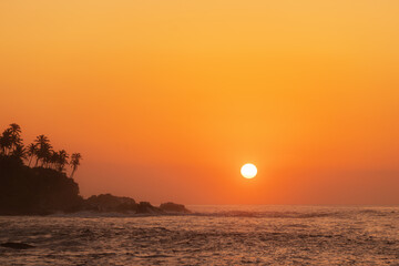 Stunning Tropical Sunset Over Ocean with Palm Trees on Coastline