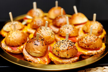 Mini burgers with cheese and sesame buns on a tray
