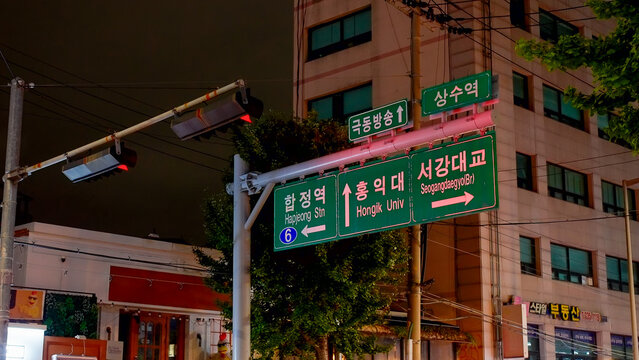 SEOUL, SOUTH KOREA - OCTOBER 11, 2025 - Green street signs in Seoul, South Korea, showing directions to Hapjeong, Hongik University, and Seogangdaegyo Bridge at night